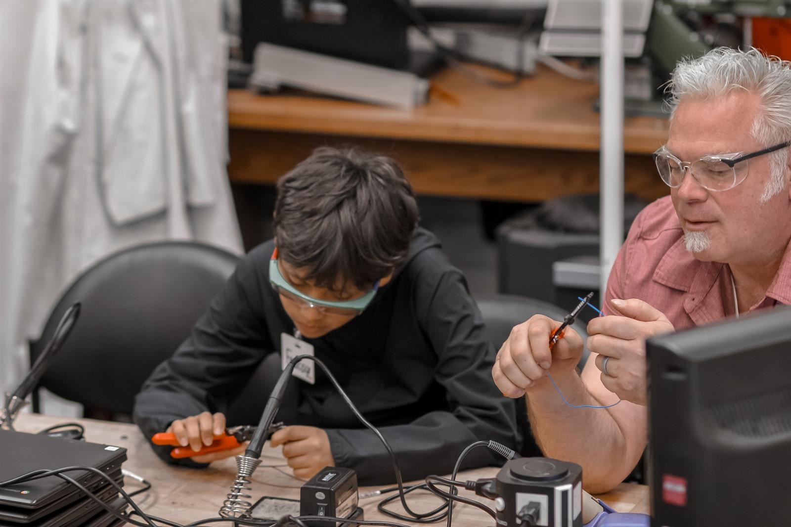  Mechatronics Engineering teacher Jim Burnham works with a student during middle school camp